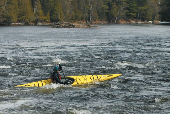 Person paddling yellow sea kayak on a river