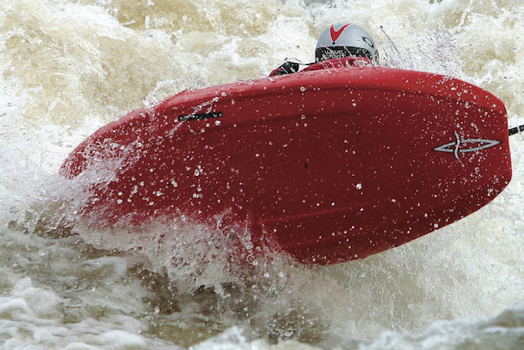 Paddler catches some air in a Pyranha Kingpin Icon whitewater kayak