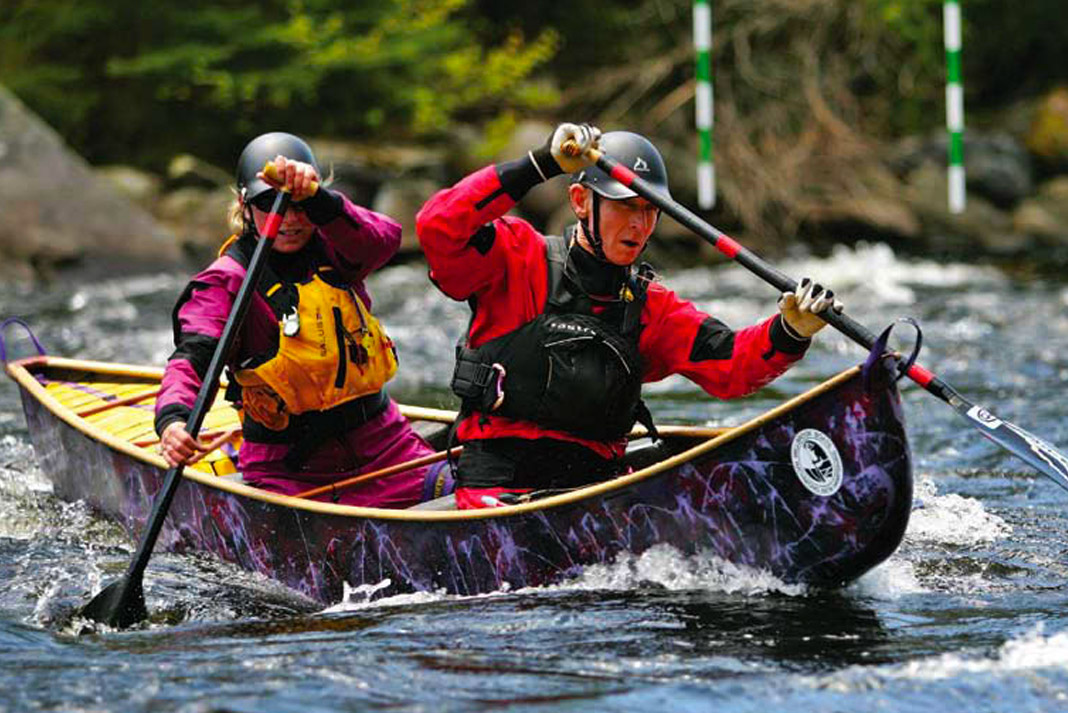Two people paddling a purple open boat.