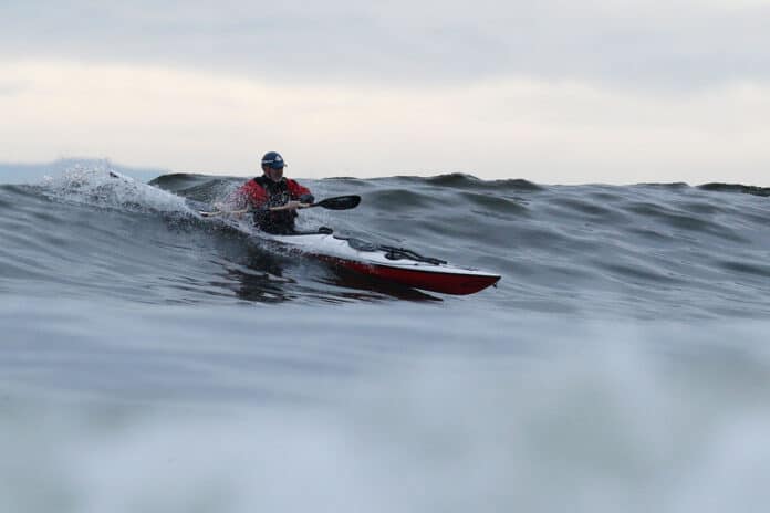 a man kayak surfing on a wave