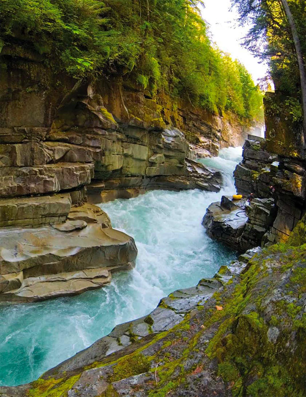 Rapids running through canyon with kayakers up on rocks