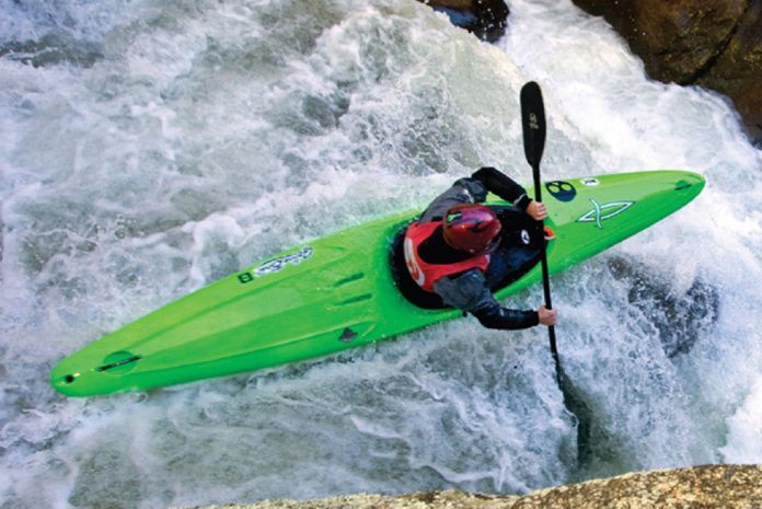 Person paddles a Dagger Green Boat kayak through river rapids
