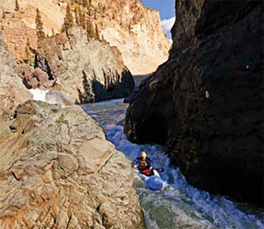 Person kayaking through narrow canyon