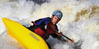 Man paddles a Titan Genesis freestyle kayak through whitewater rapids