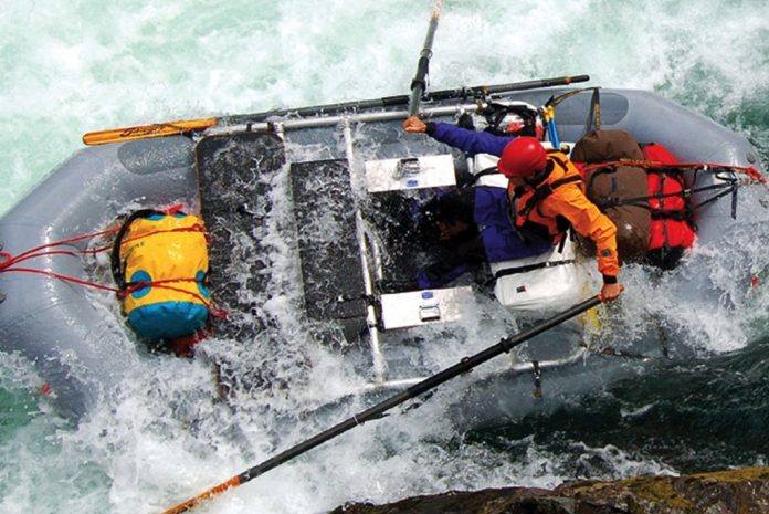 Single person manning oars on a raft in whitewater