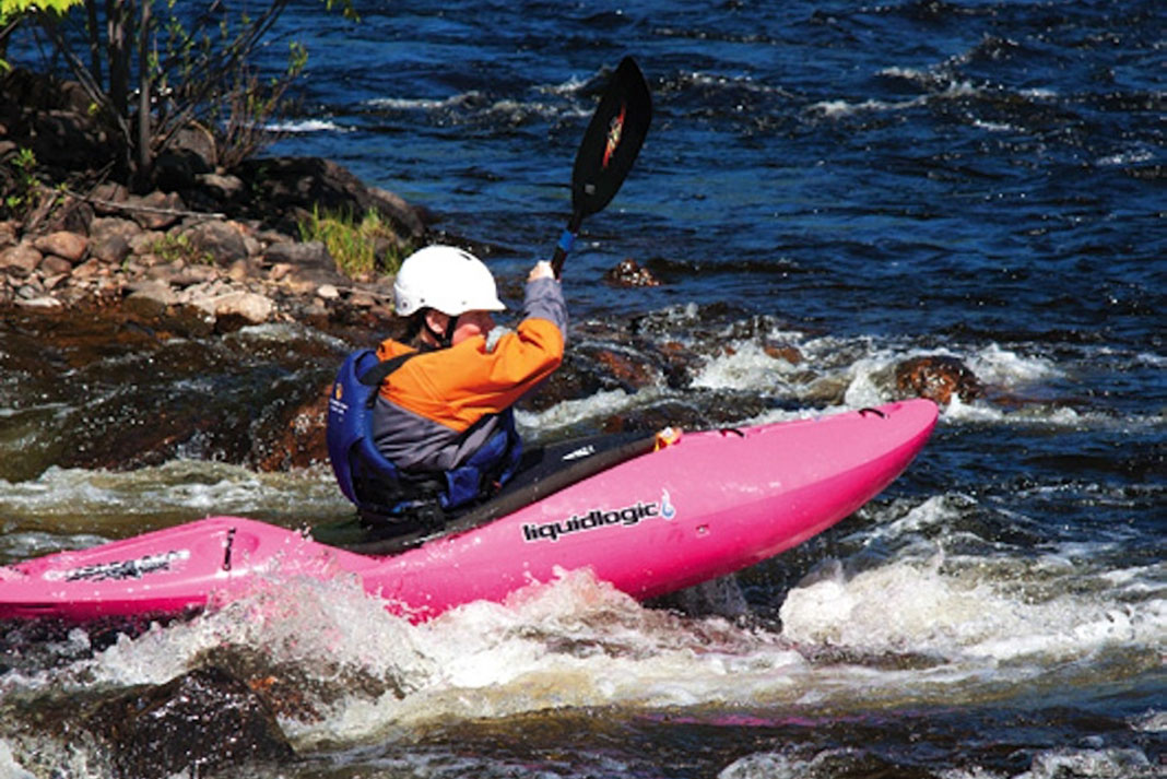 Woman paddles through rapids in a Liquidlogic Stomper kayak