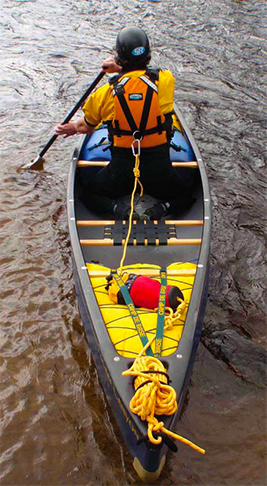 Man paddling canoe solo with rope attached to the back of his PFD.