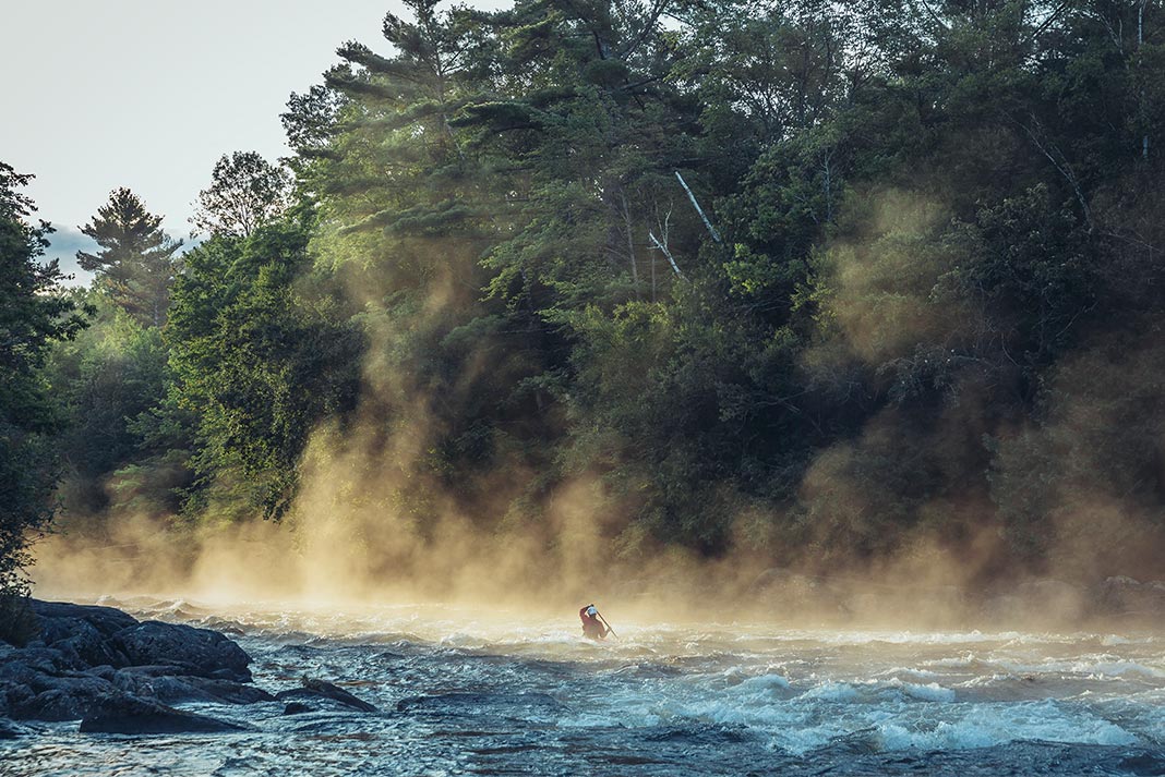 Person paddling on river with mist rising up