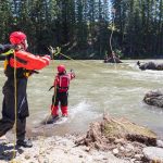 Whitewater Rescue Skill: How To Use A Throw Bag Three people on shore, one person throwing a throw rope to person in the water