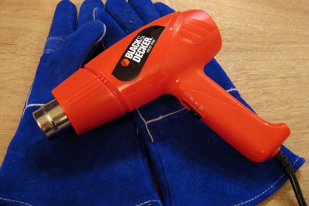 Orange heat gun laying on blue work gloves