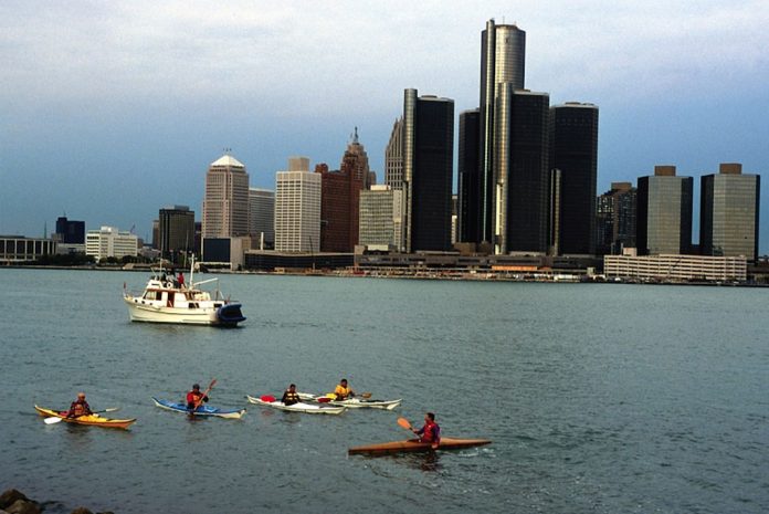 A group kayaking in front of the Detroit skyline on the Detroit River