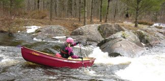 Woman paddling open boat down a rapid