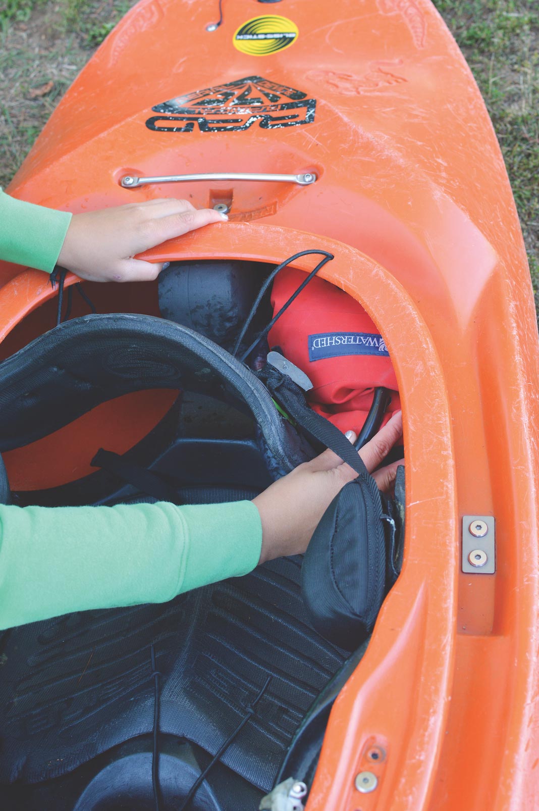 Someone placing floatation bag behind seat of kayak