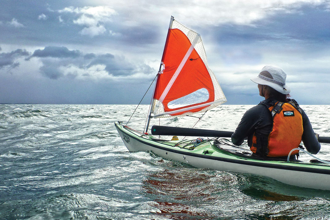 Person on a kayak with sail at the front