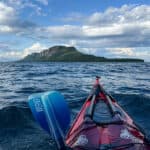 How To Paddle In A Straight Line In Wind And Current bow shot of a sea kayak paddling in a straight line across open water to the dramatic Sleeping Giant