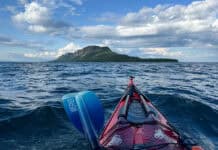 bow shot of a sea kayak paddling in a straight line across open water to the dramatic Sleeping Giant