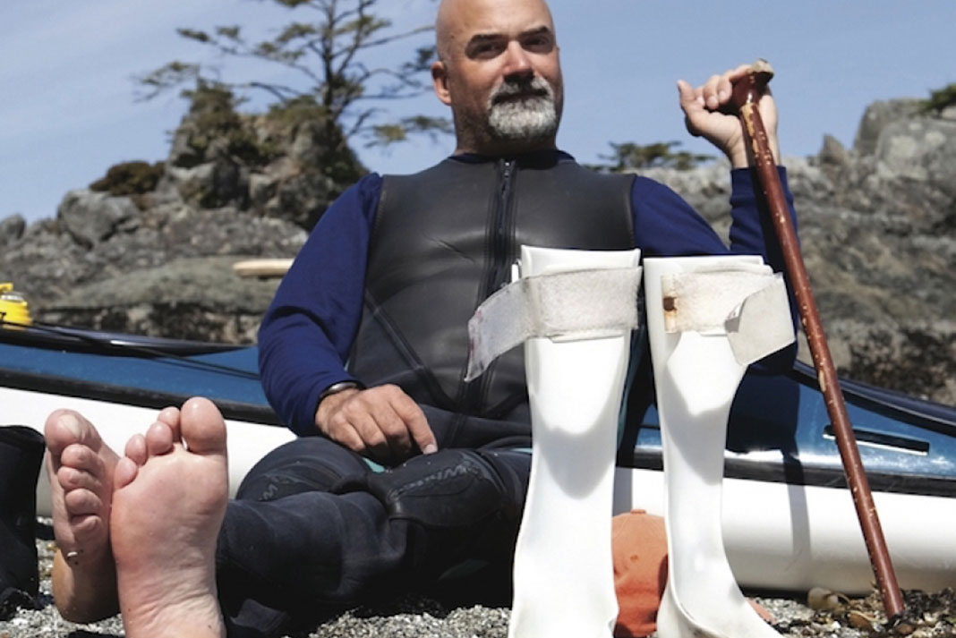 Man with a spinal cord injury sits on the beach after kayaking