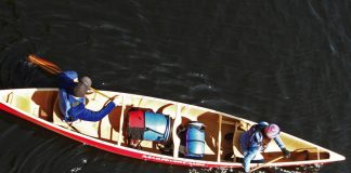 Overhead view of two people in red canoe with blue barrels