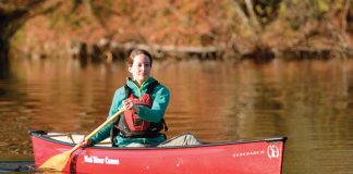 Woman paddling red solo canoe