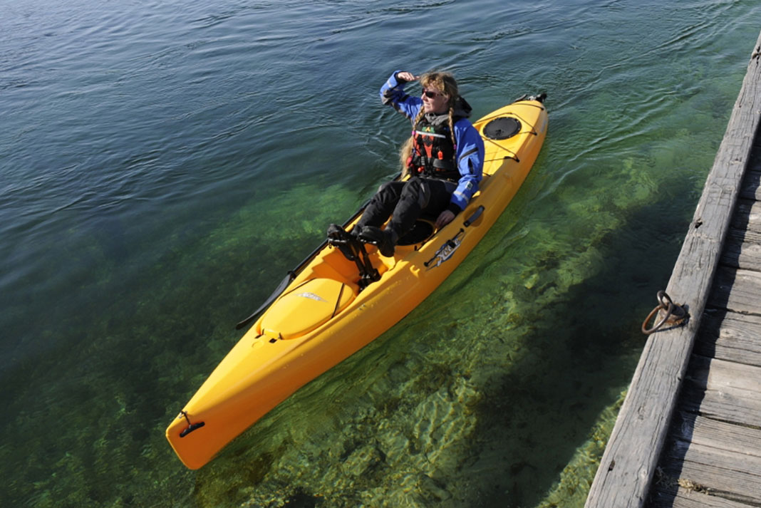 Woman floats on clear water in the Hobie Mirage Revolution 13 kayak