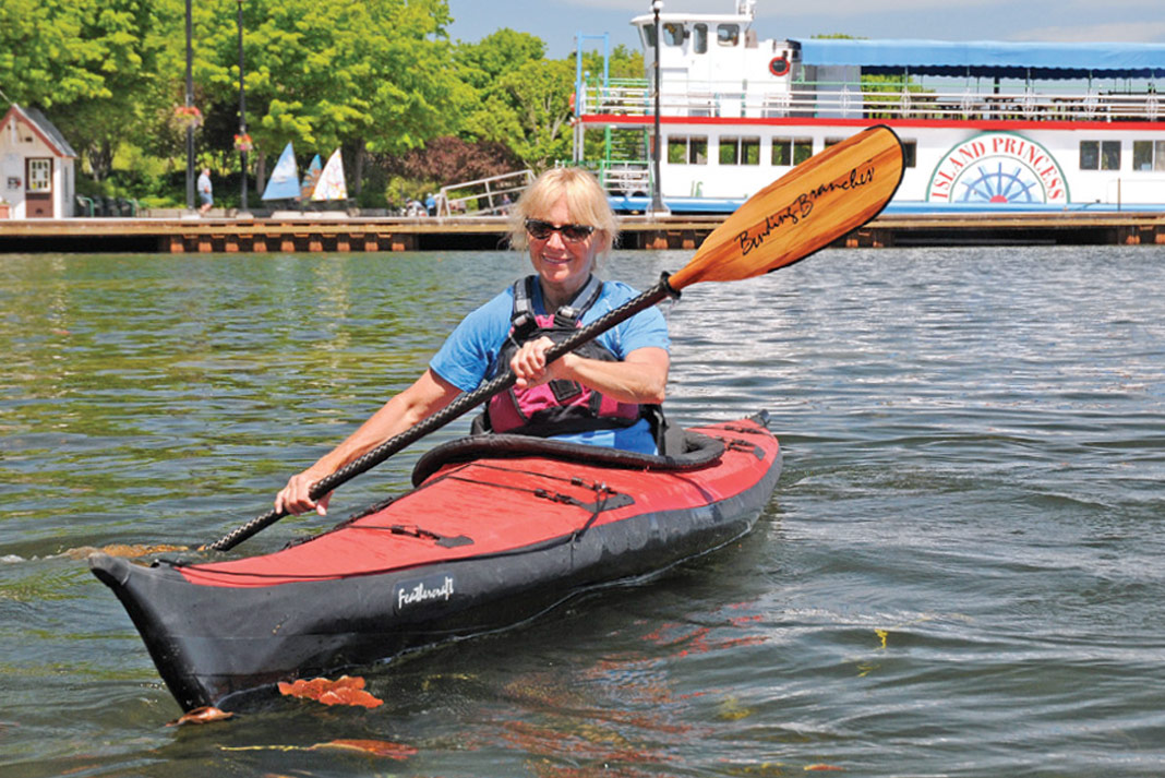 Woman paddling red folding touring kayak