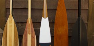Five canoe paddles lined up along wall