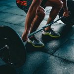 How To Use Strength Training to Improve Your Kayaking Performance Man grabbing barbell at bottom of deadlift motion.
