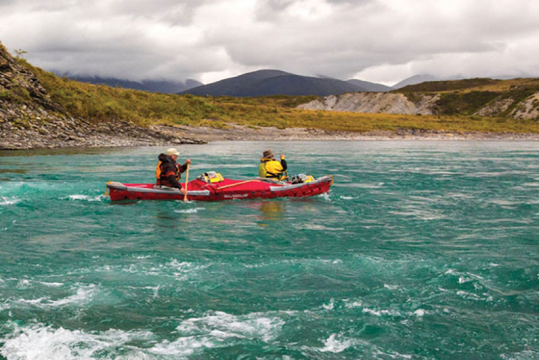 Two people paddle through turquoise water in the Pakboats PakCanoe 170