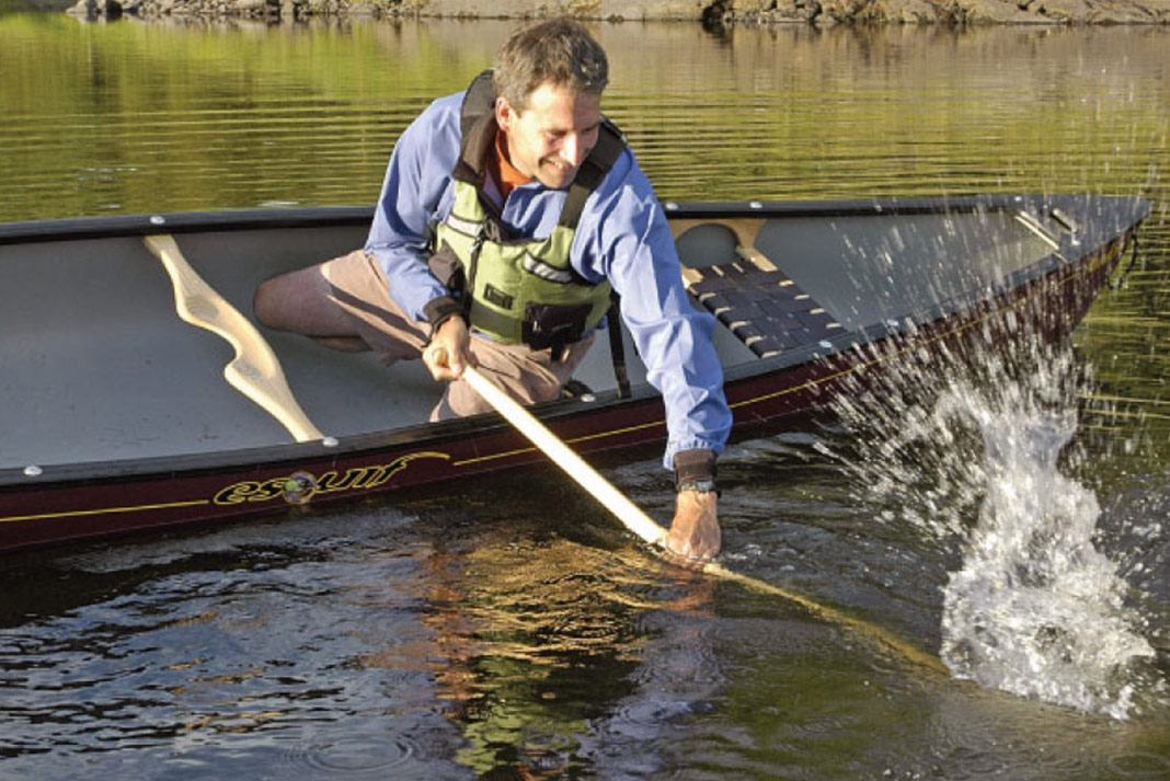 Man solo in canoe leaning to do a brace