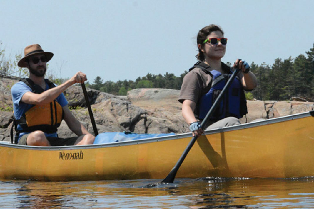 Man and woman tandem paddling in a Wenonah Minnesota II canoe