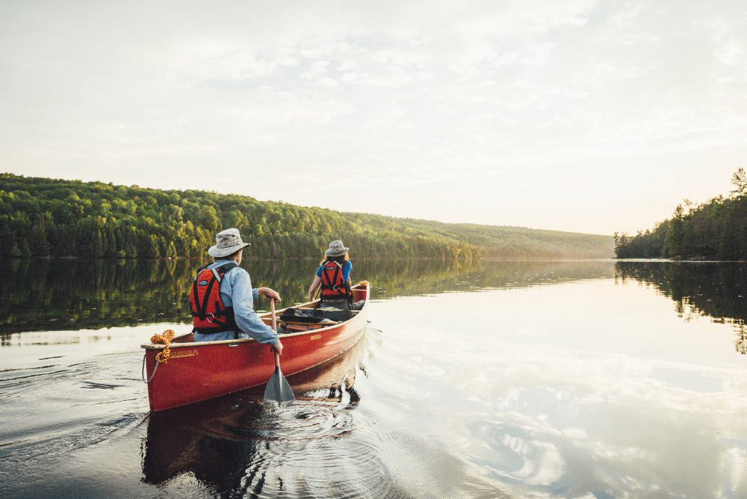 Two people paddling canoe across calm lake