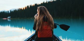 A woman in the bow of a canoe on a blue lake