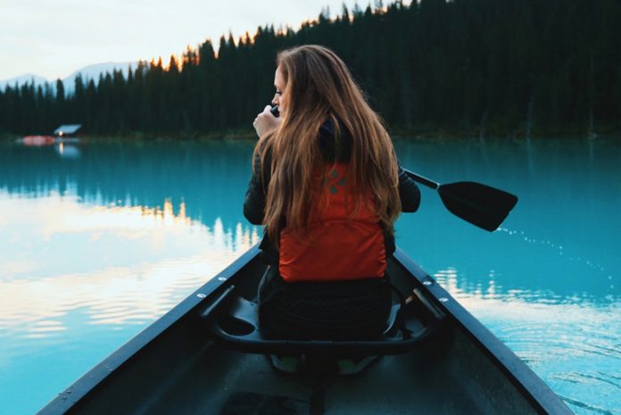 A woman in the bow of a canoe on a blue lake
