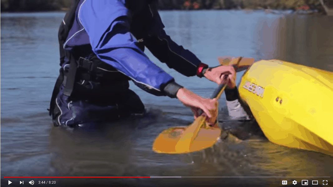 Instructor helps someone roll their kayak.