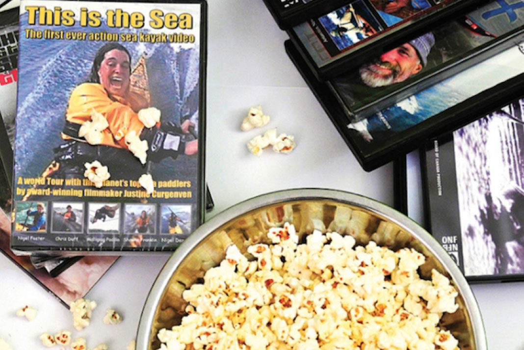 Bowl of popcorn beside stacks of DVDs