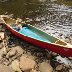 Get The Best Backcountry Sleep Ever—In Your Canoe Man lying in a canoe pulled up on shore.