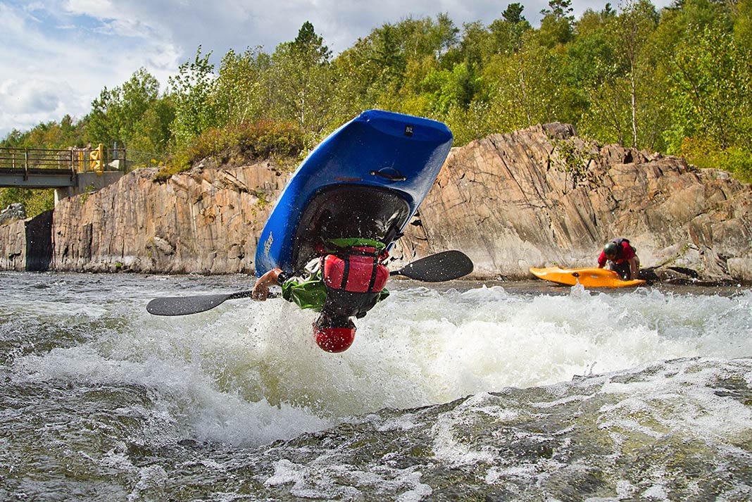 Person in blue whitewater kayak doing a flip