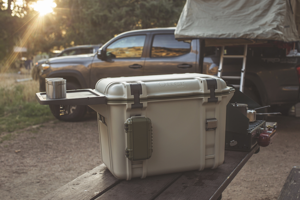 A venture cooler from Otterbox sits on the bed of a truck in the sunshine.