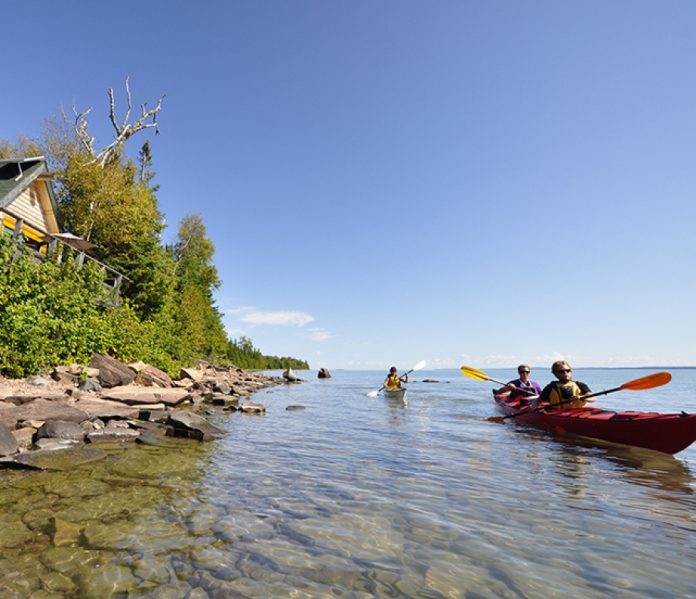 one solo kayak and one tandem kayak paddling on flat water