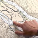 How To Plan A Safe Kayak Trip A kayaker plans his trip on a map before going out on the water.