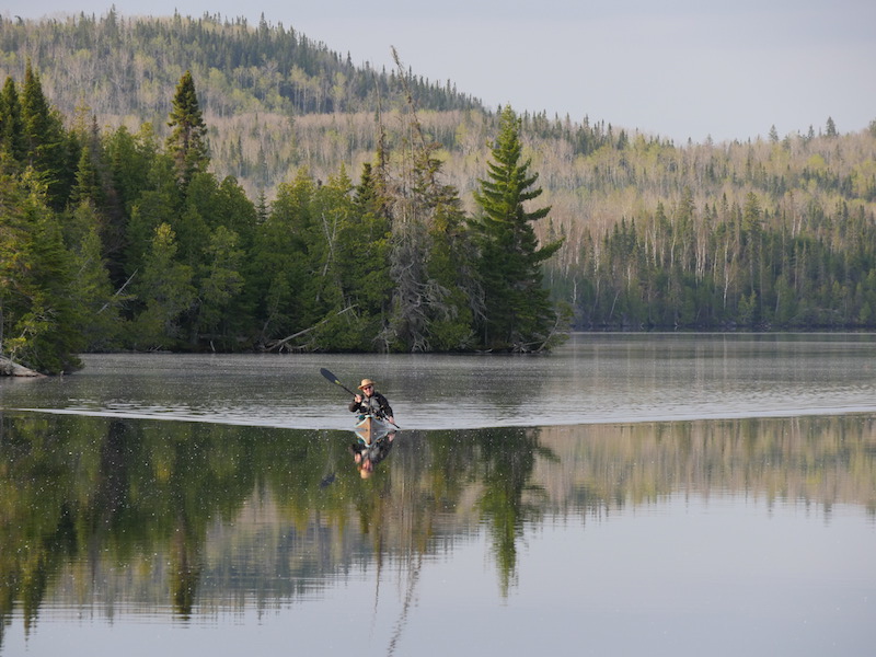 A canoeist on a glossy lake 