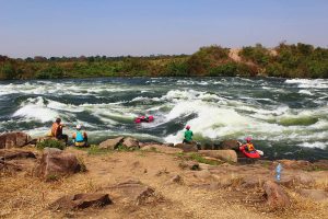 While Brooke Hess surfs, others enjoy the sunshine on Uganda's Victoria Nile.