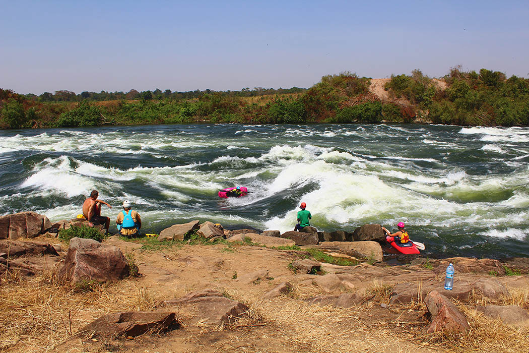 While Brooke Hess surfs, others enjoy the sunshine on Uganda's Victoria Nile. 