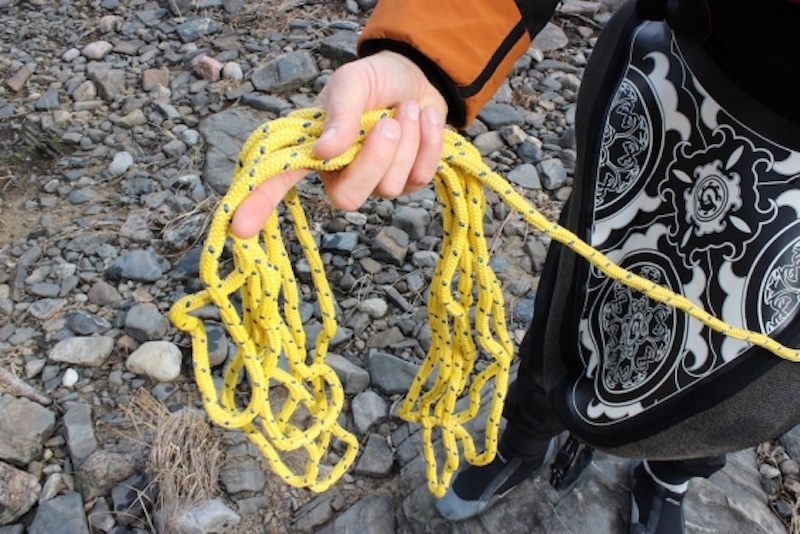 A whitewater kayaker holds a rope for a coil rescue in his hands. 