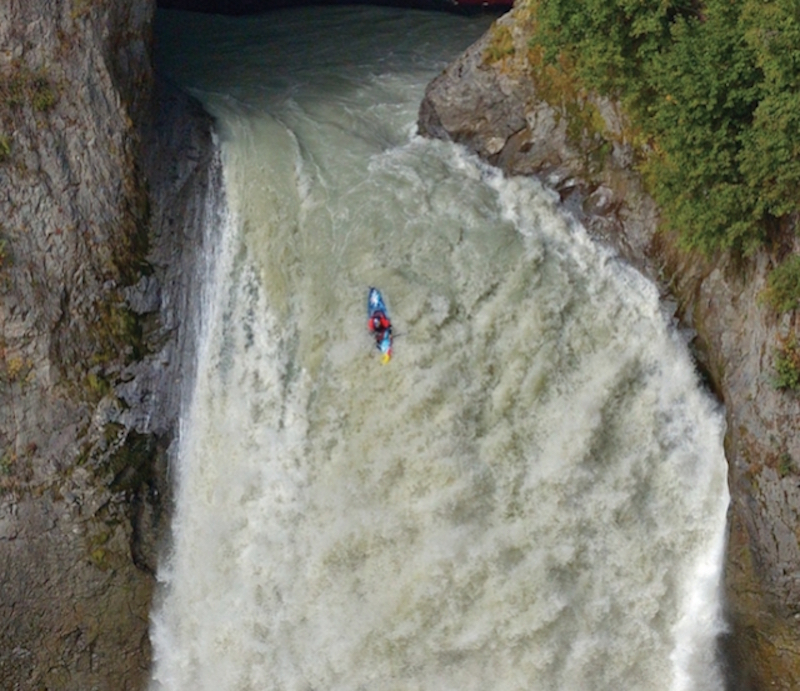 A kayaker rides a big waterfall. 