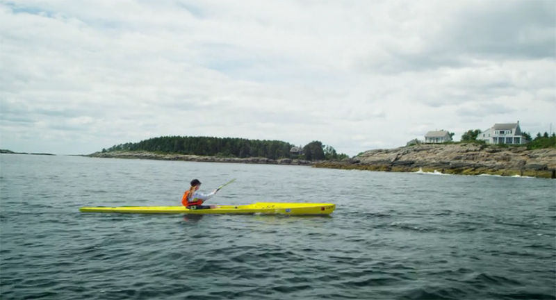 Traci Lynn Martin paddles a yellow kayak on the ocean.