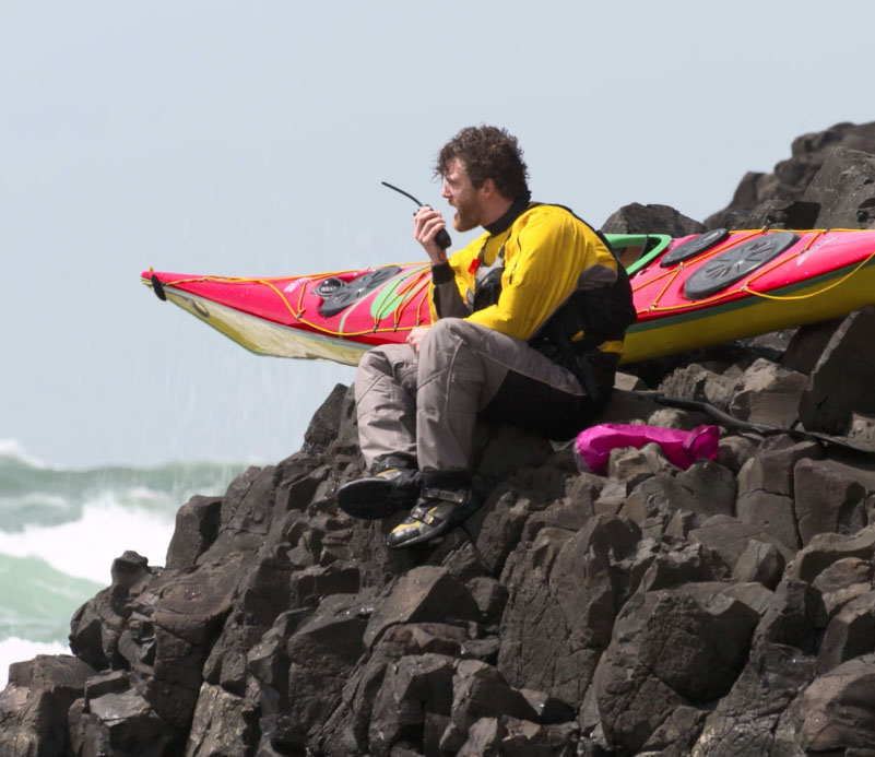 A stranded kayaker is beached on the rocks due to unpredictable wind and weather.