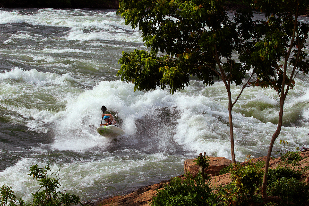 A whitewater kayaker surfs on the Nile Special wave on the Victoria Nile in Uganda during winter 2017
