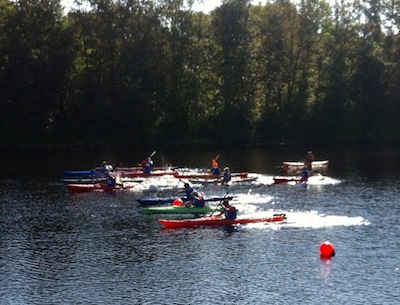 A group of kayakers compete in a flatwater kayak race