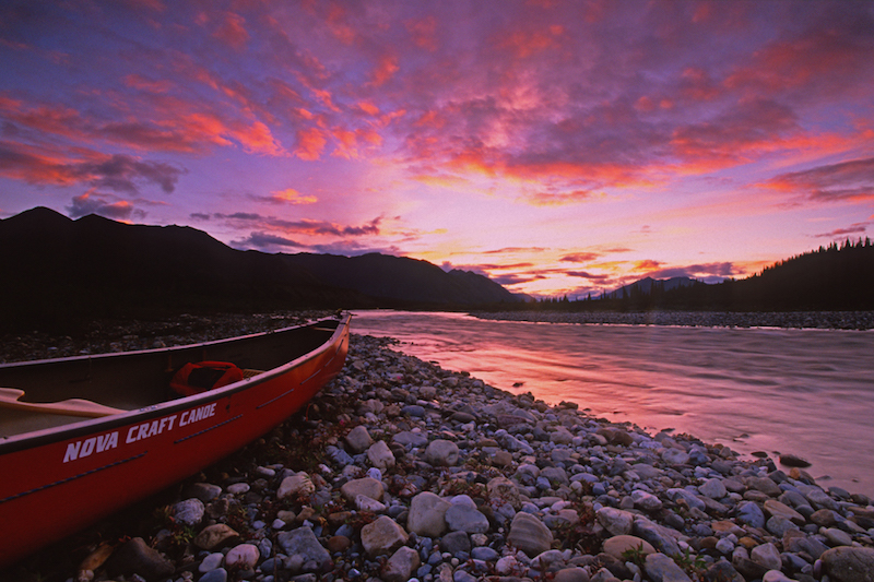 A beautiful purple Yukon River sunset with a red canoe in the foreground